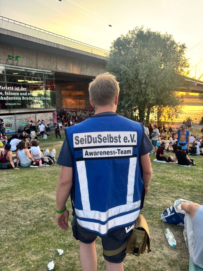 Mitglied des Awareness-Teams von SeiDuSelbst e.V. während einer Laufpräsenz durch die Besucherinnenmenge beim CSD Düsseldorf 2025.